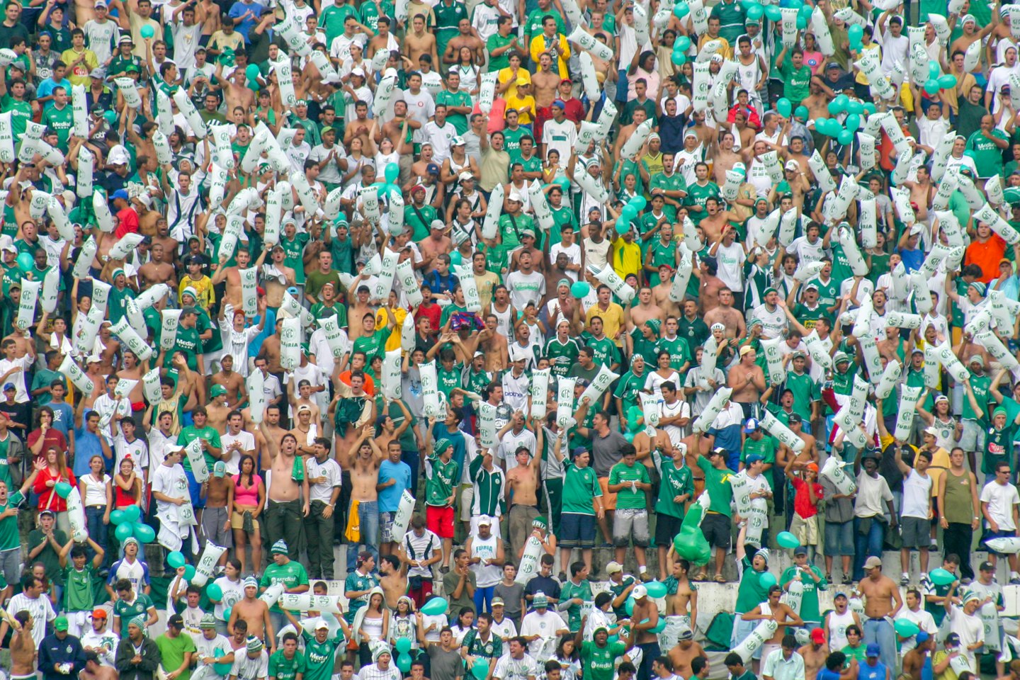 Begeisterte Sportfans jubeln mit aufblasbaren Schlägern und Luftballons.