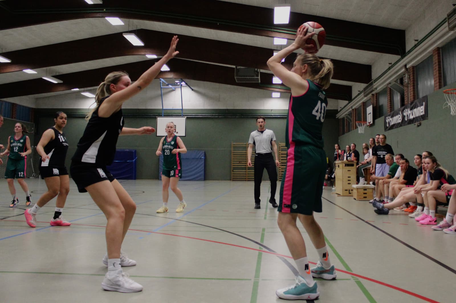 Spielerin im grünen Trikot wirft den Ball, die Gegnerin verteidigt