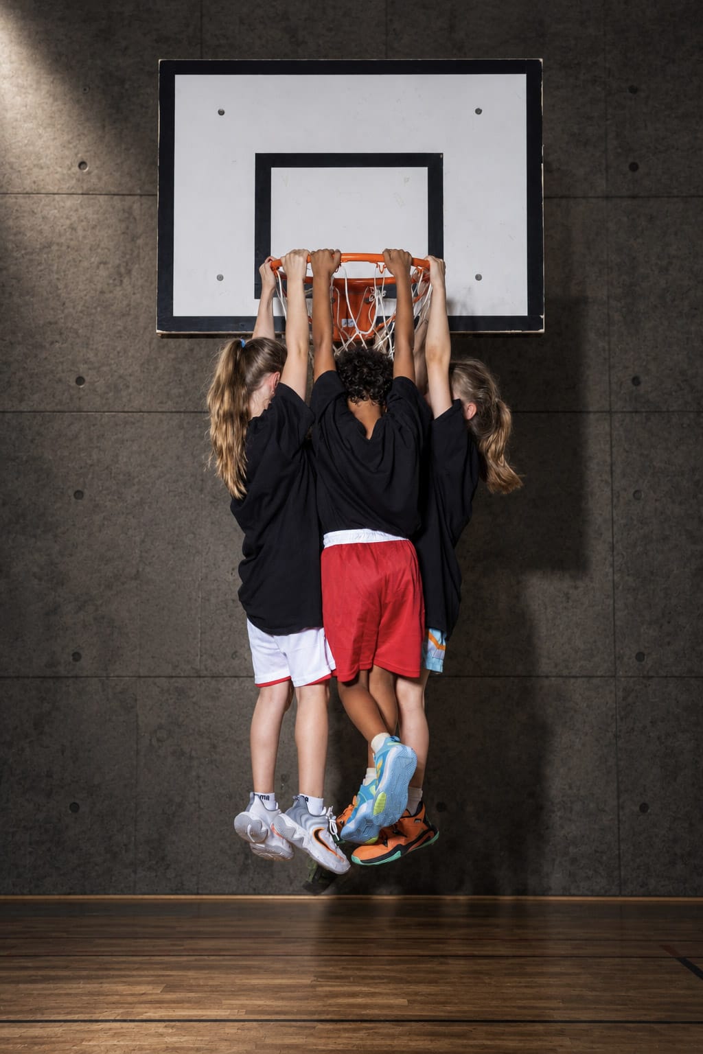 Drei Spielerinnen hängen am Basketballkorb